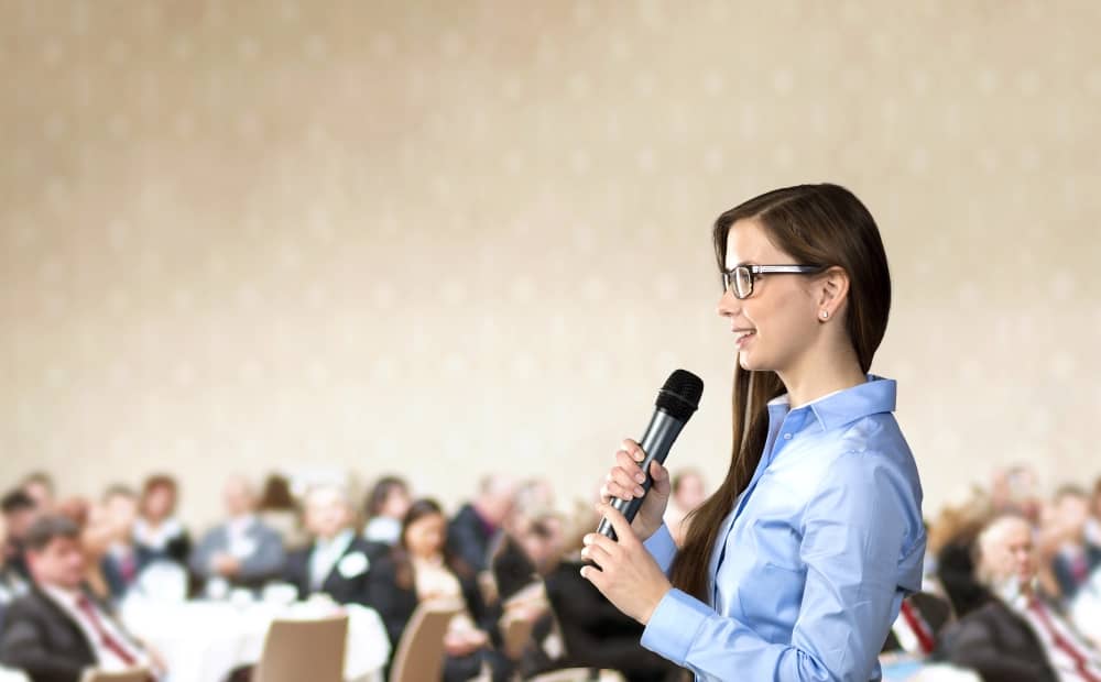 female-presenter-speaking-in-front-of-audience